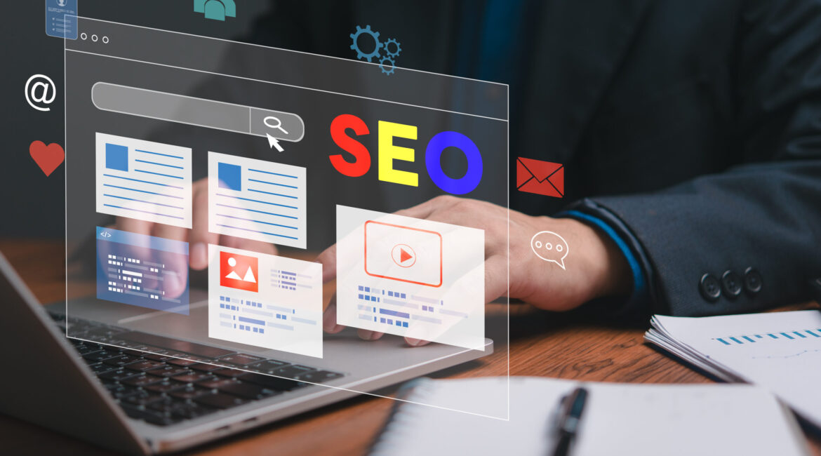 A man is typing on a laptop with a screen displaying a website with the words SEO on it